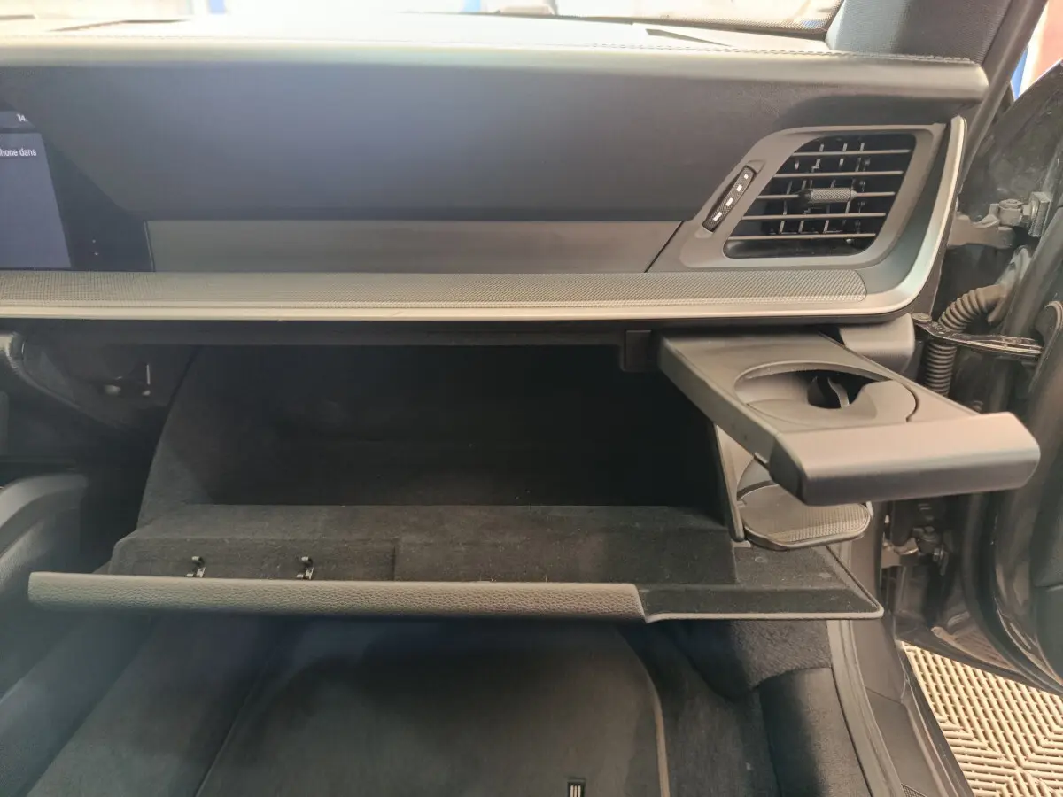 Vue intérieure côté passager du coffre à gants ouvert avec porte-gobelet déployé sur Porsche 911 Carrera 4S Coupé gris foncé.