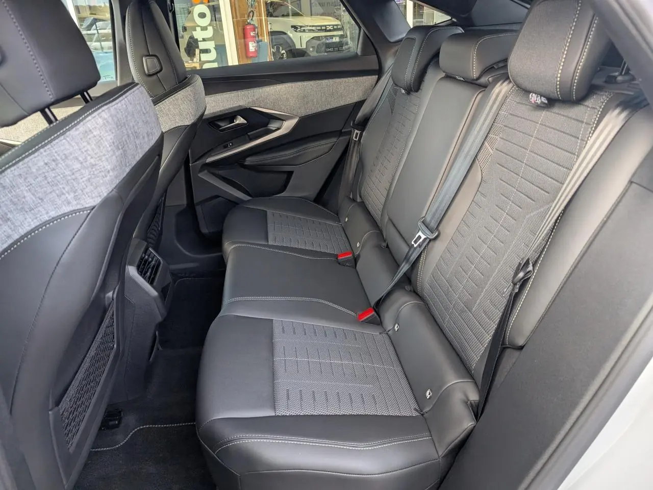 Vue côté droit de la banquette arrière en tissu gris et cuir noir du Peugeot 3008 blanc, avec ceinture de sécurité et appuie-têtes.