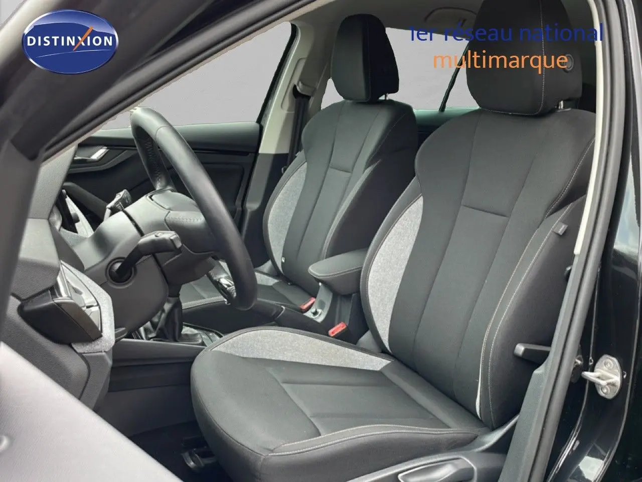 Vue intérieure côté conducteur de la Skoda Scala 2025 noir magique métal, sièges tissu bicolore gris et noir.