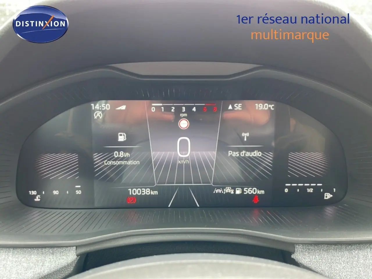 Vue rapprochée du tableau de bord numérique de la Skoda Scala noir magique métal, affichant la vitesse à 0 km/h et la consommation.