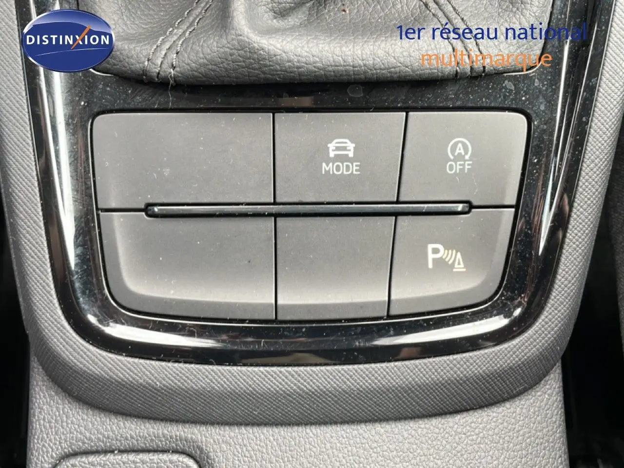 Gros plan sur les boutons de commande du mode de conduite et assistance parking d'une Skoda Scala noire.