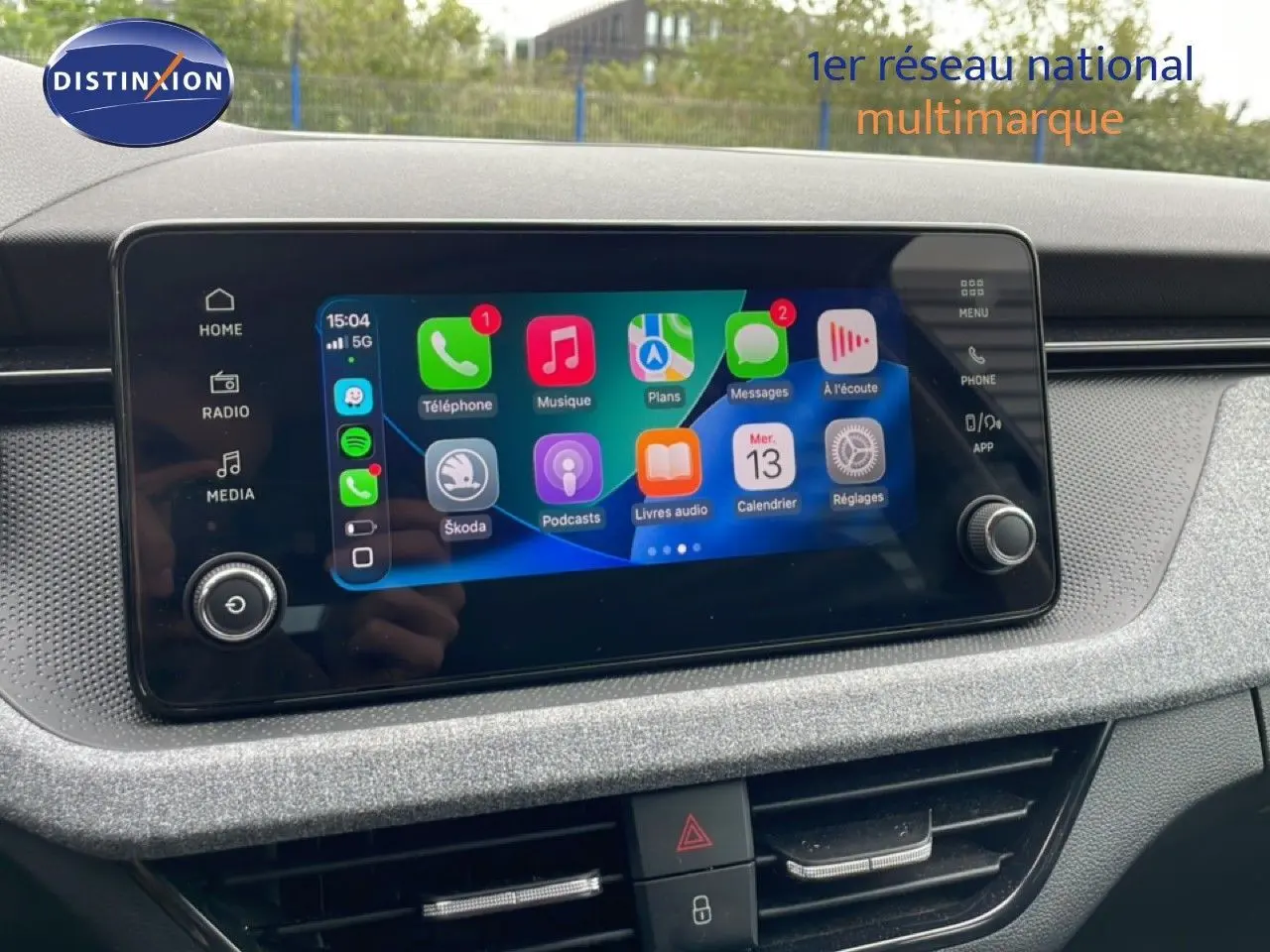 Écran tactile central du Skoda Scala 2025 noir magique métal, affichant Apple CarPlay avec icônes colorées.