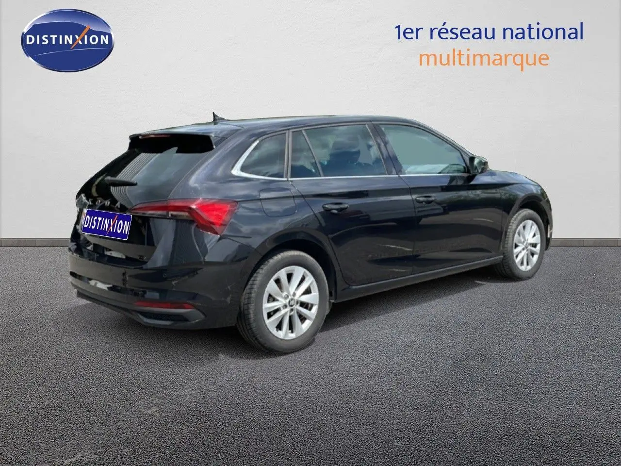Vue 3/4 arrière droite d’une Skoda Scala noire métallisée avec jantes argentées sur fond neutre.