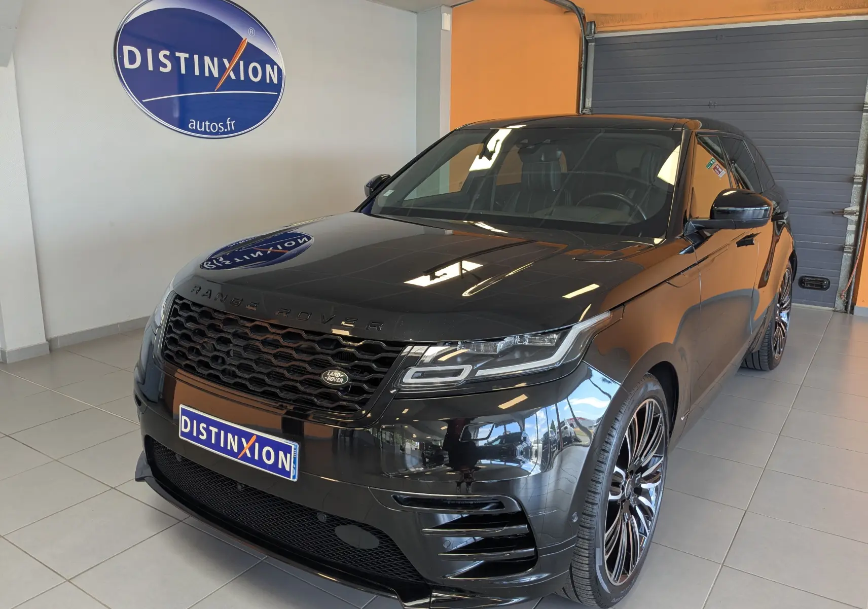 Vue 3/4 avant d'un Range Rover Velar noir brillant avec calandre hexagonale et jantes alliage noires en concession.