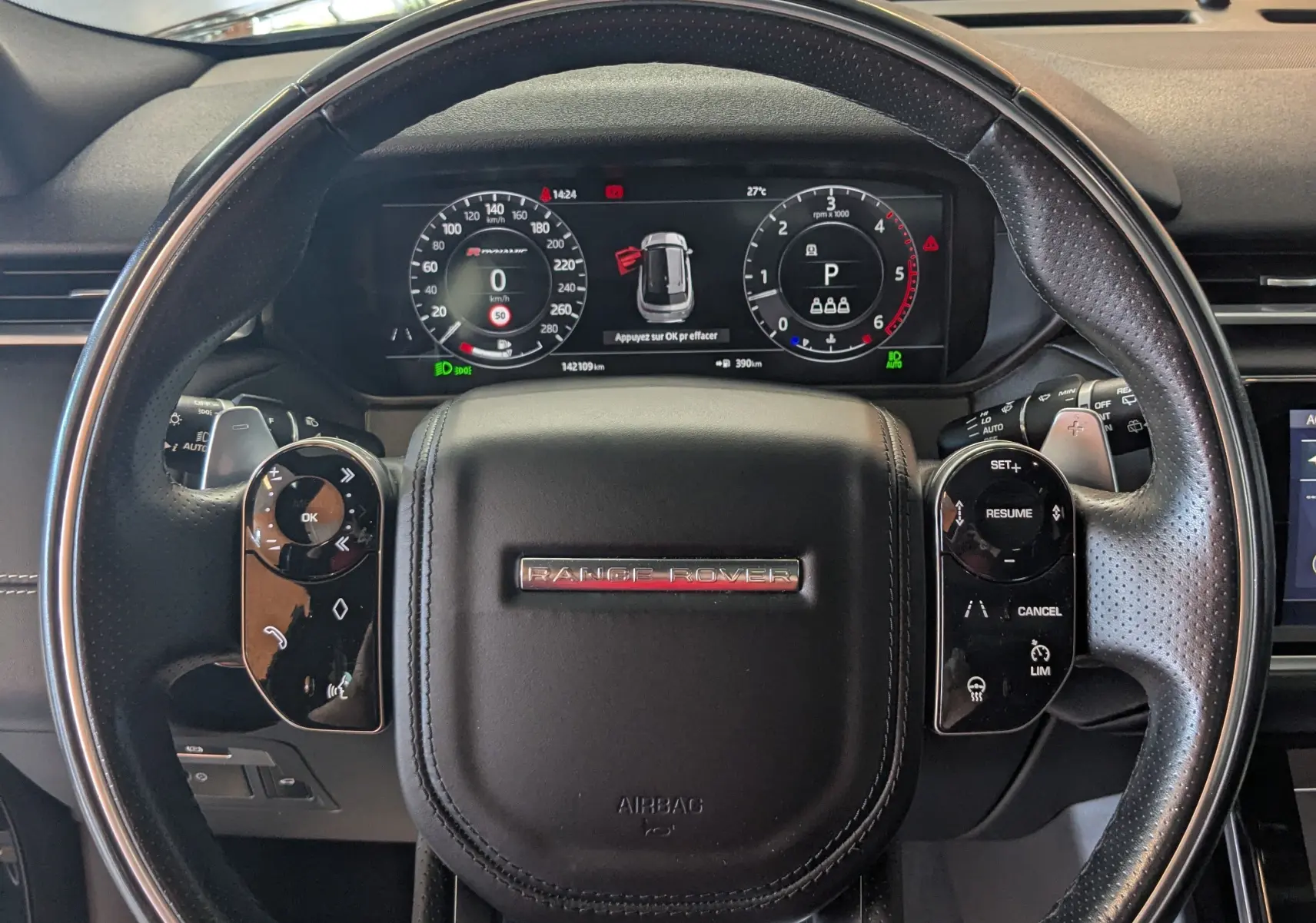 Vue rapprochée du volant noir du Range Rover Velar 2020 avec tableau de bord numérique et commandes intégrées.