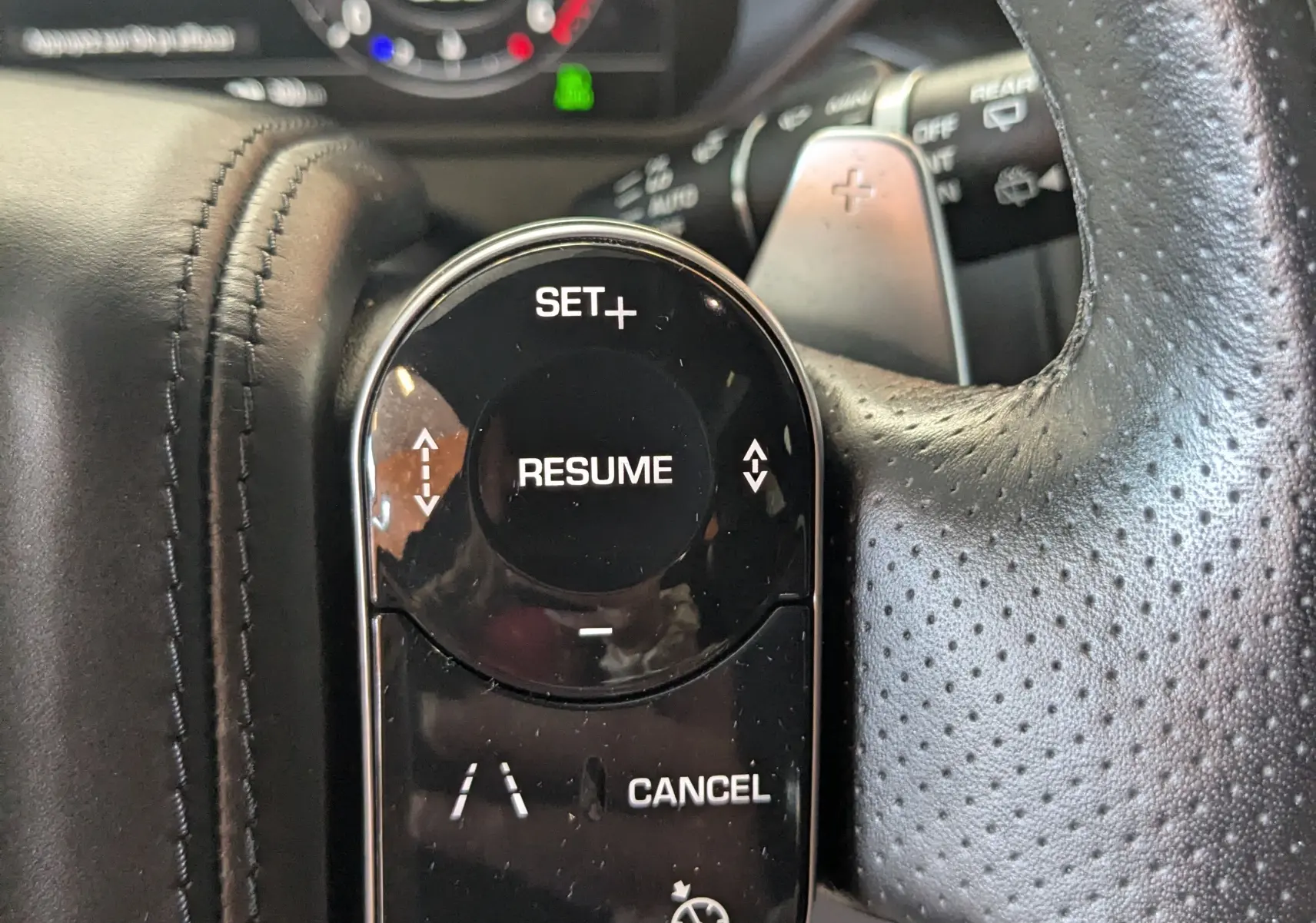 Gros plan sur les commandes noires du régulateur de vitesse au volant perforé du Range Rover Velar 2020 noir.