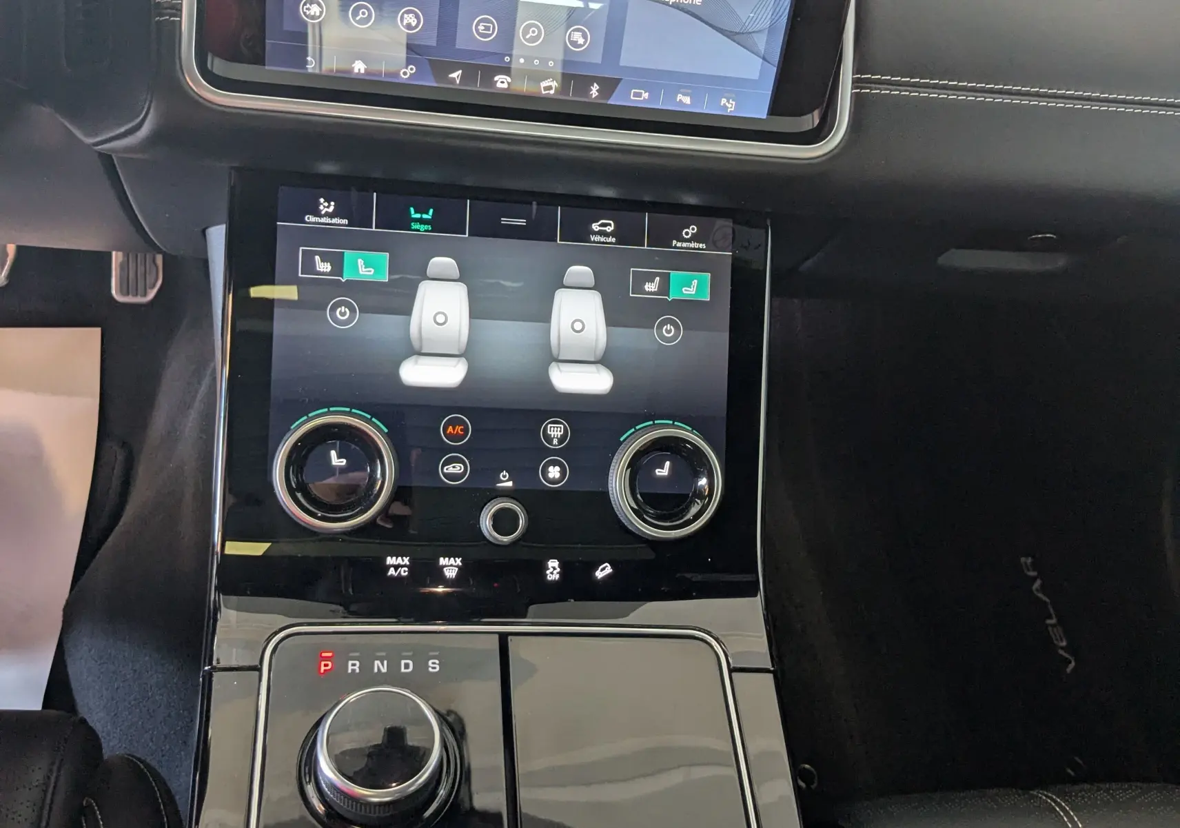 Vue rapprochée de la console centrale noire du Range Rover Velar 2020 avec écran tactile et molette de boîte auto.