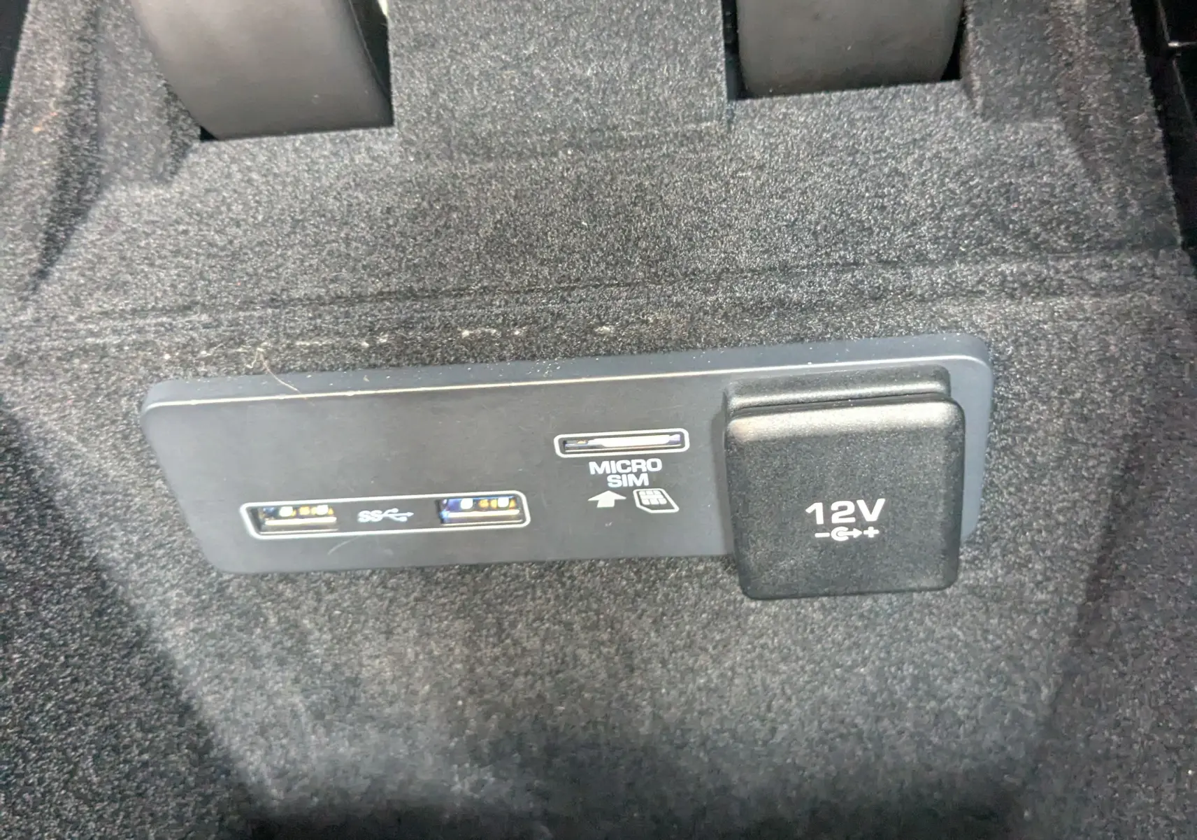 Gros plan sur la prise 12V et ports USB avec emplacement micro SIM dans l'habitacle noir du Range Rover Velar 2020.