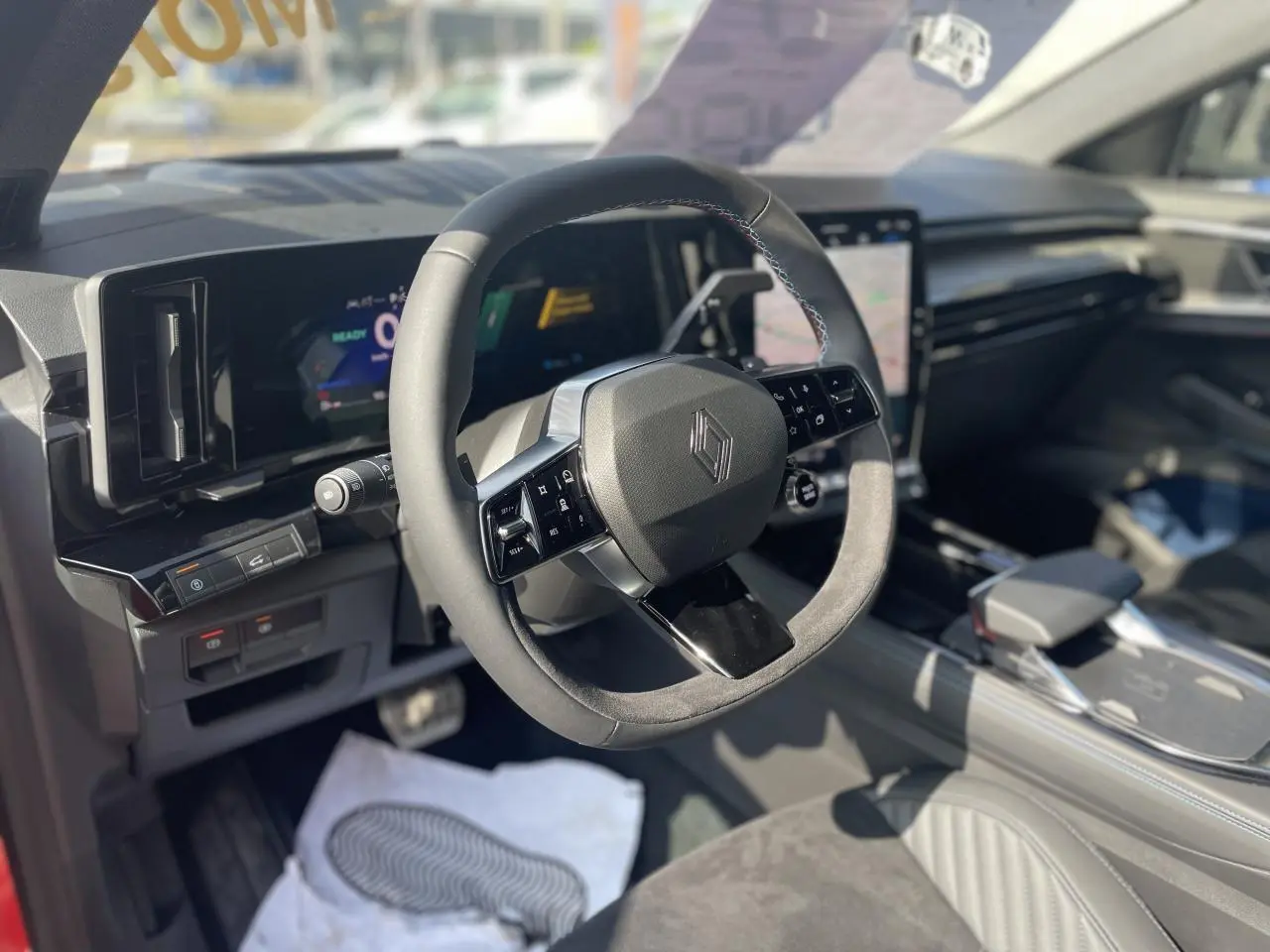 Intérieur Renault Rafale 2025 vu côté conducteur, volant Alcantara avec surpiqûres tricolores et écran tactile vertical.