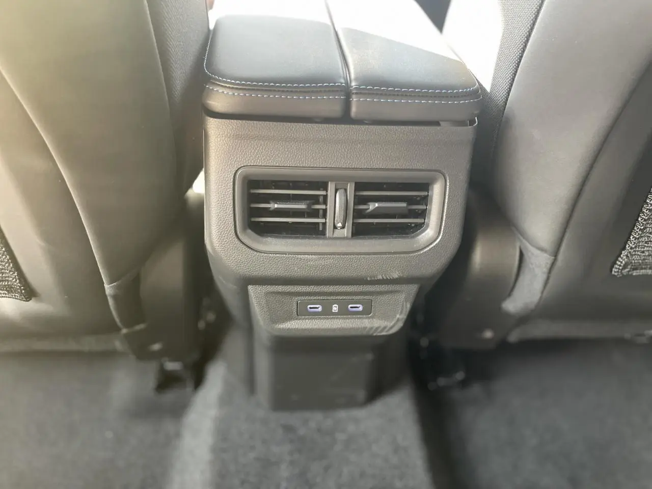 Prise USB-C et bouche d'aération arrière sur la console centrale noire entre les sièges arrière d'une Renault Rafale rouge toit noir.