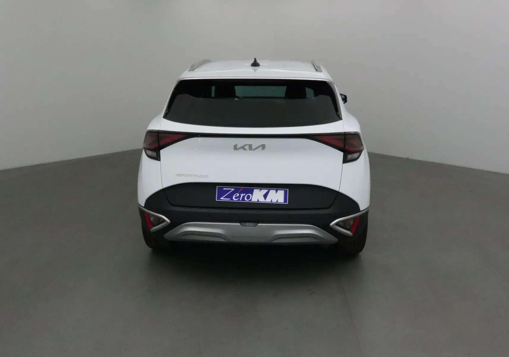 Vue arrière du SUV blanc KIA SPORTAGE 2025 avec feux LED et logo KIA moderne sur fond neutre.