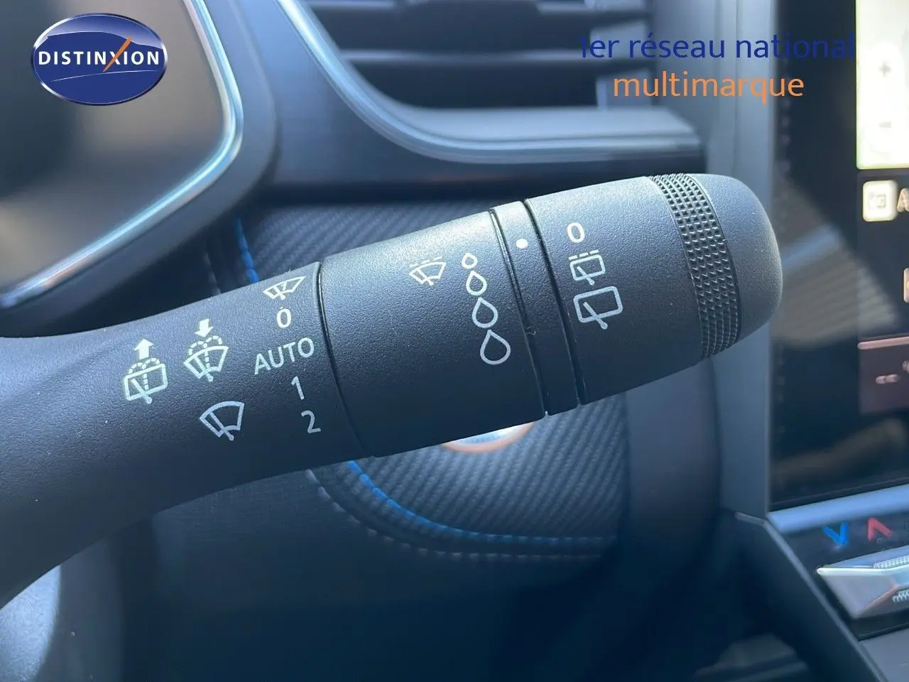 Gros plan sur la commande d’essuie-glace du Renault Captur E-Tech hybride 2025, intérieur noir avec surpiqûres bleues.