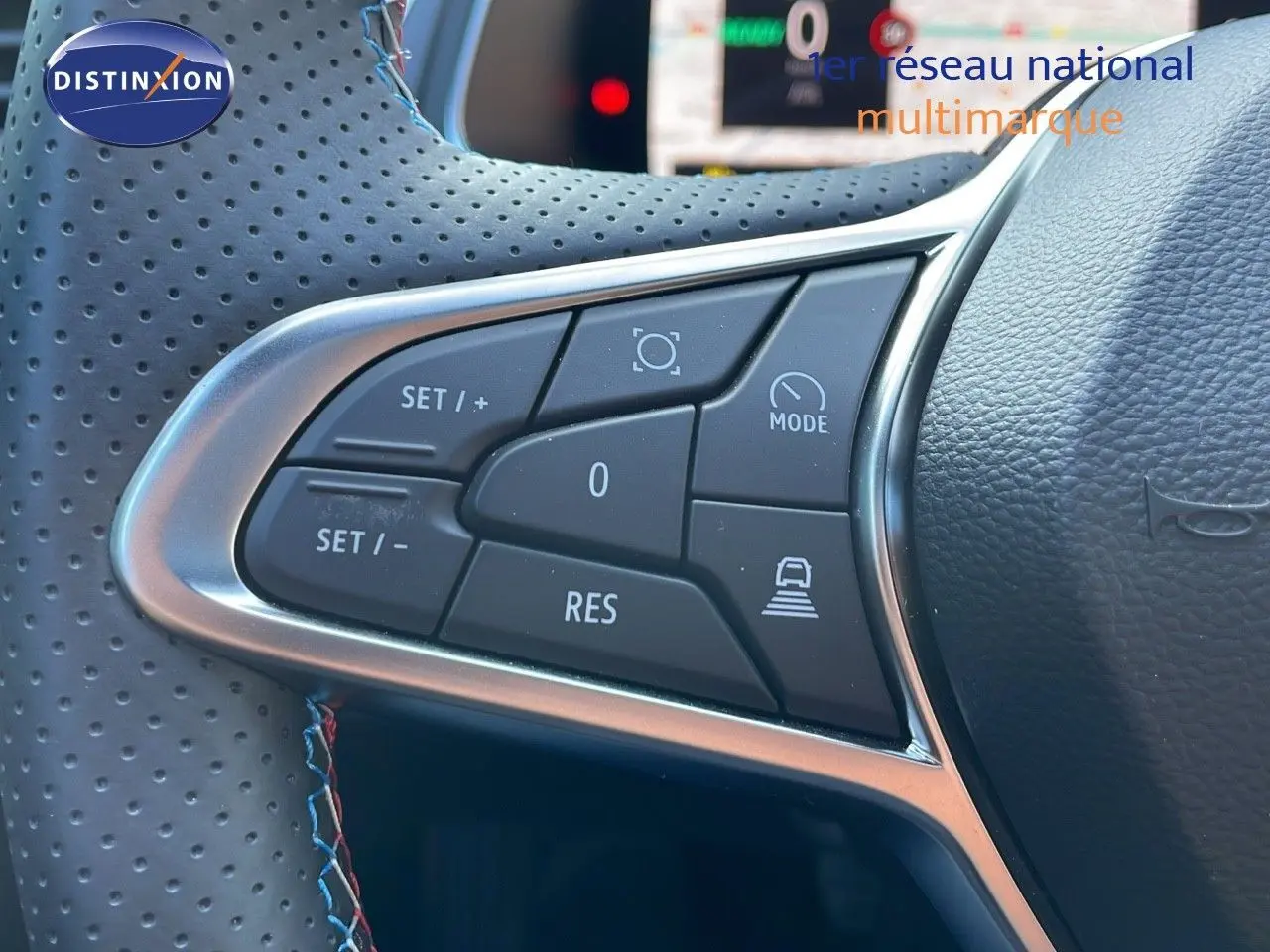 Gros plan sur les commandes de régulateur de vitesse au volant cuir perforé du Renault Captur E-Tech bleu iron métal toit noir.