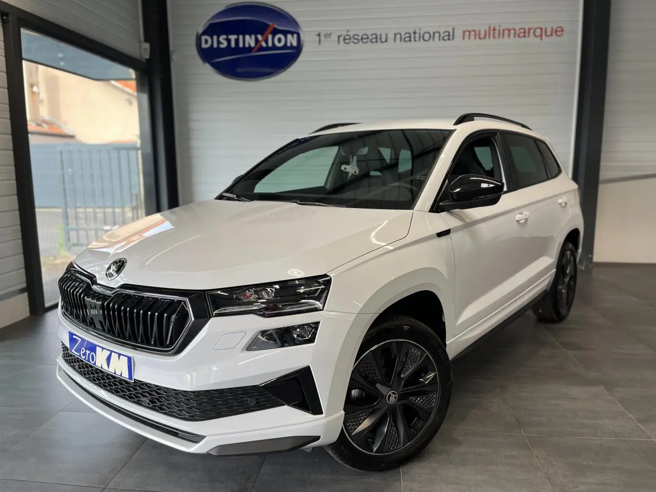Vue 3/4 avant droite d’un SUV Skoda Karoq blanc 2025 avec calandre noire et jantes alliage noires Sportline.