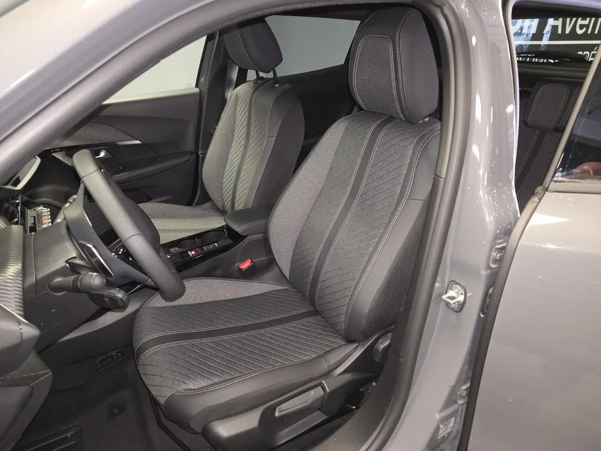 Vue intérieure côté conducteur du PEUGEOT 2008 gris 2025, mettant en valeur les sièges tissu et TEP avec surpiqûres Quartz.