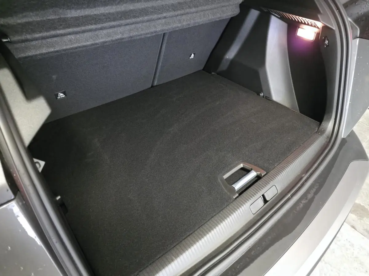 Vue intérieure du coffre spacieux et propre du Peugeot 2008 gris, éclairé par une lampe intégrée sur le côté droit.