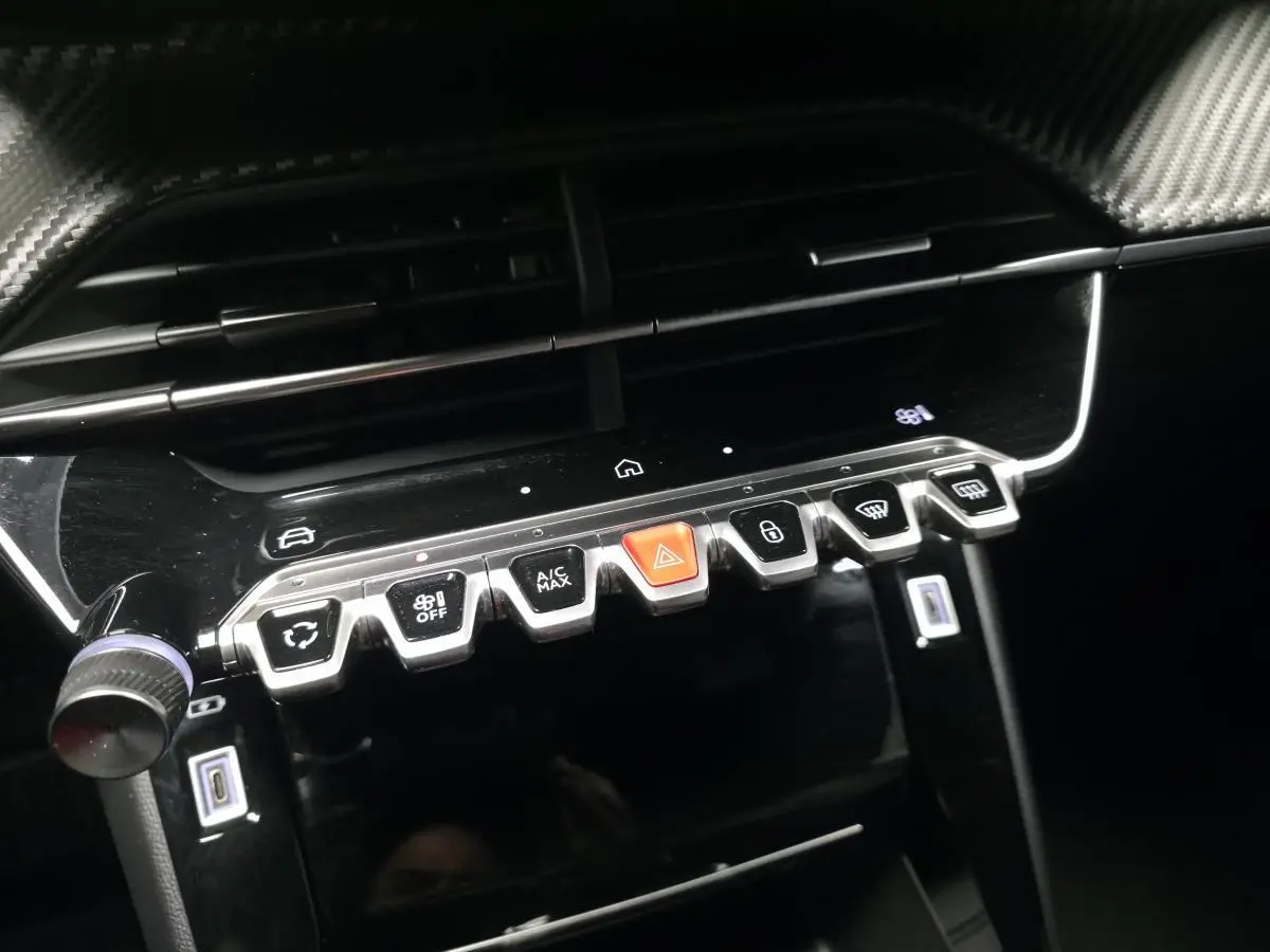 Gros plan sur la console centrale noire brillante du Peugeot 2008 2025 avec boutons de commande et prises USB type C.