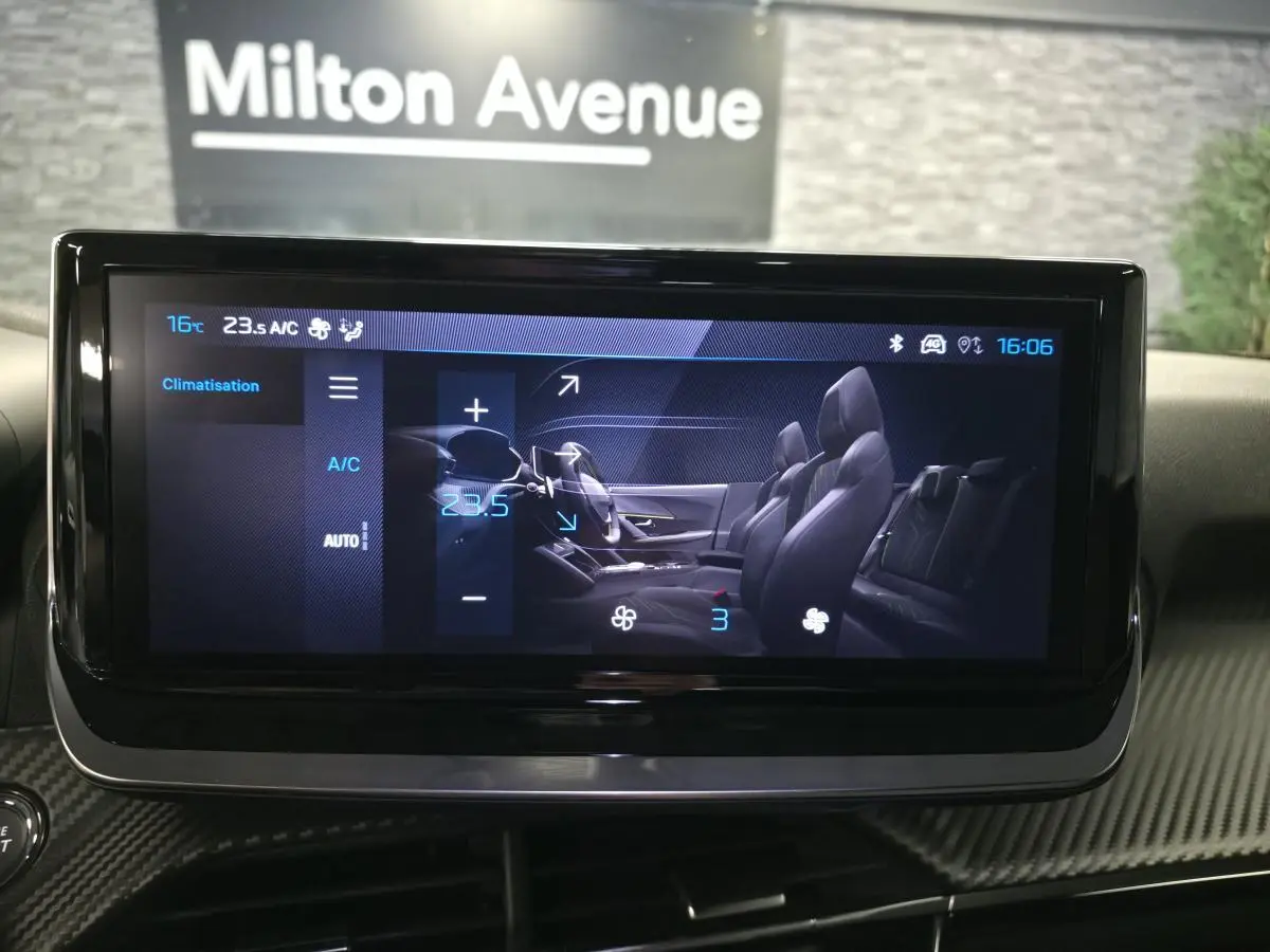 Écran tactile intérieur affichant la climatisation de la Peugeot 2008 1.2i Hybrid 2025 avec vue latérale des sièges noirs.