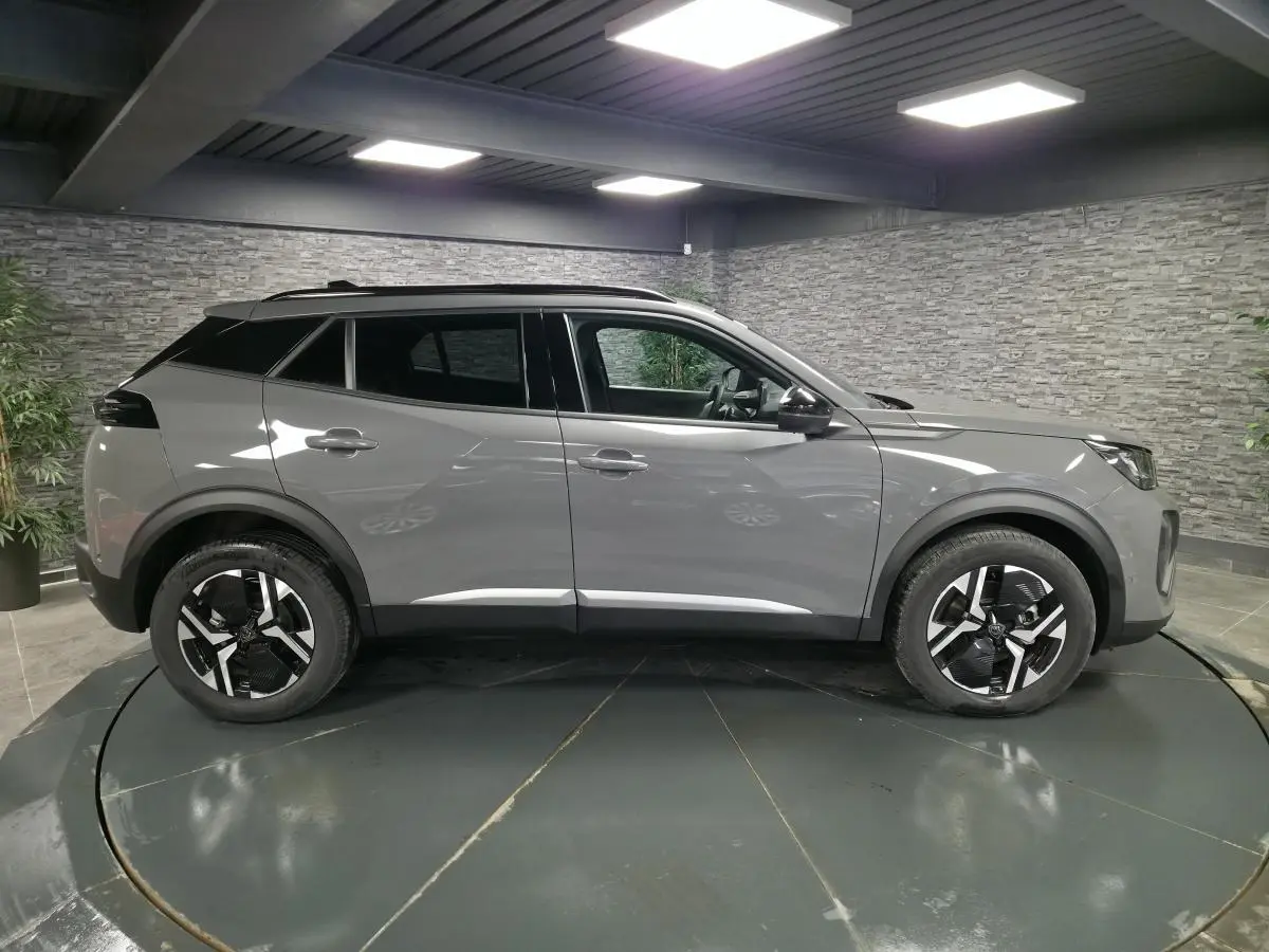 Vue latérale droite du Peugeot 2008 gris métallisé 2025 avec jantes alliage bi-ton et toit noir contrasté.