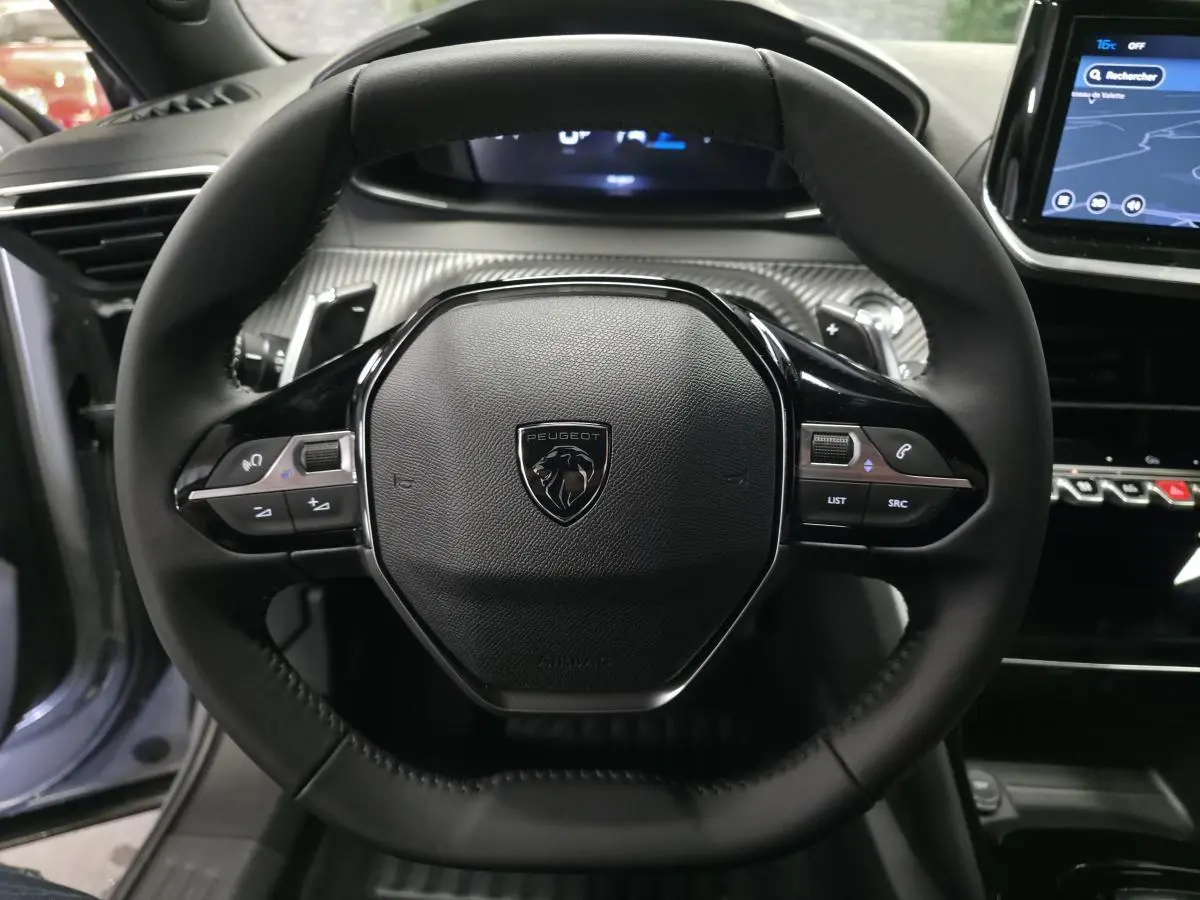 Vue rapprochée du volant compact noir de la Peugeot 2008 2025 avec commandes multimédia intégrées.