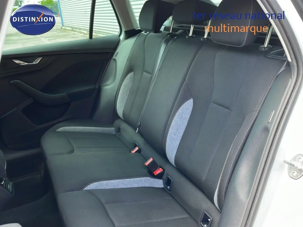 Vue intérieure de la banquette arrière du Skoda Scala blanc glacier, avec sièges tissu gris et noir à inserts clairs.