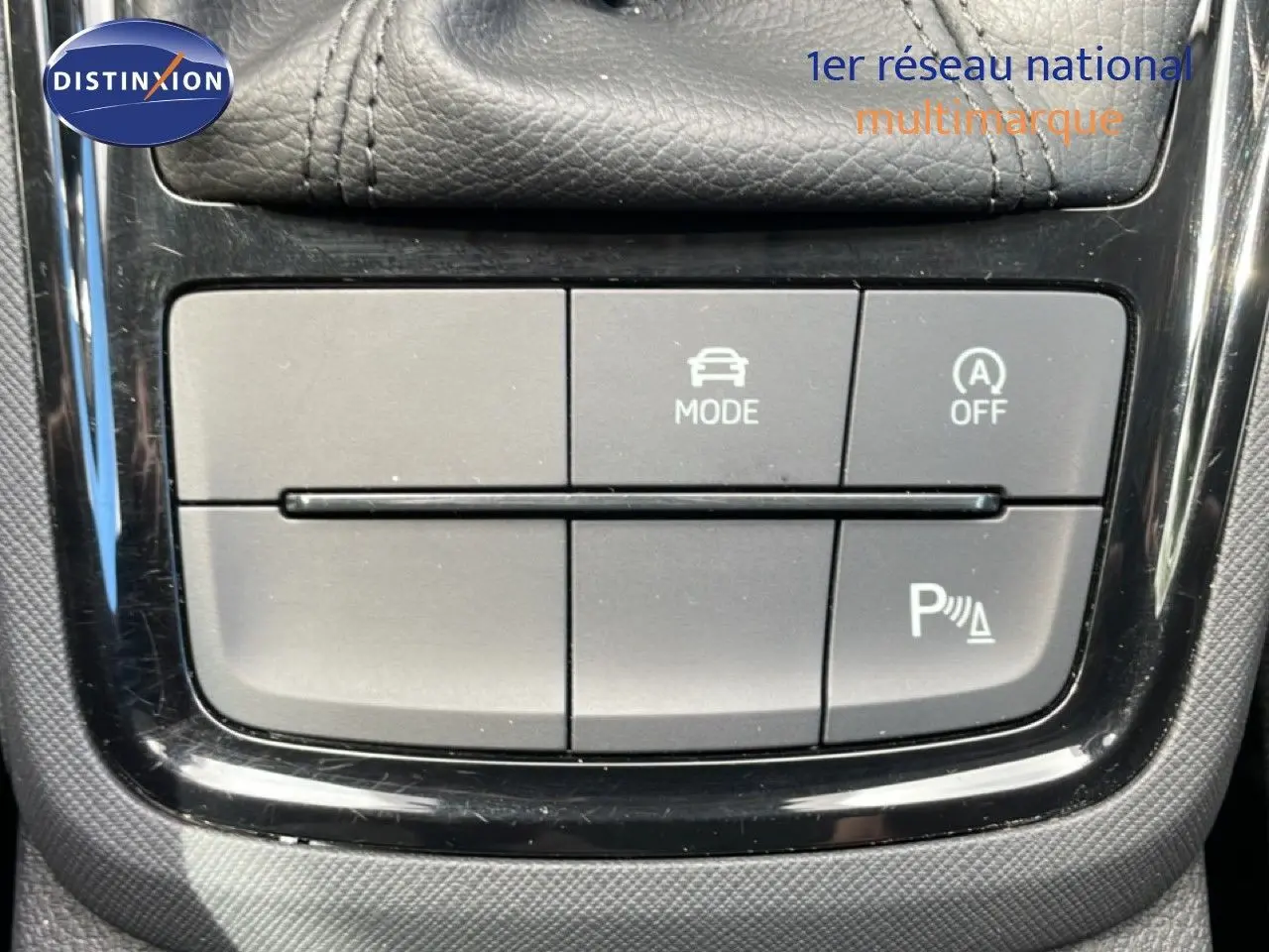 Gros plan sur les boutons de commande du mode de conduite et de l'aide au stationnement dans une Skoda Scala blanc glacier.