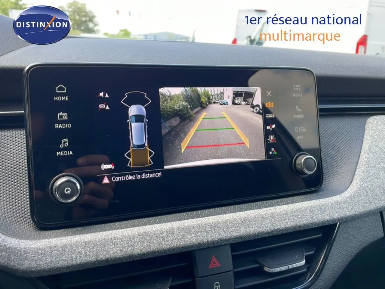 Écran central de la Skoda Scala blanc glacier 2025 montrant la caméra de recul avec guidage de trajectoire coloré.