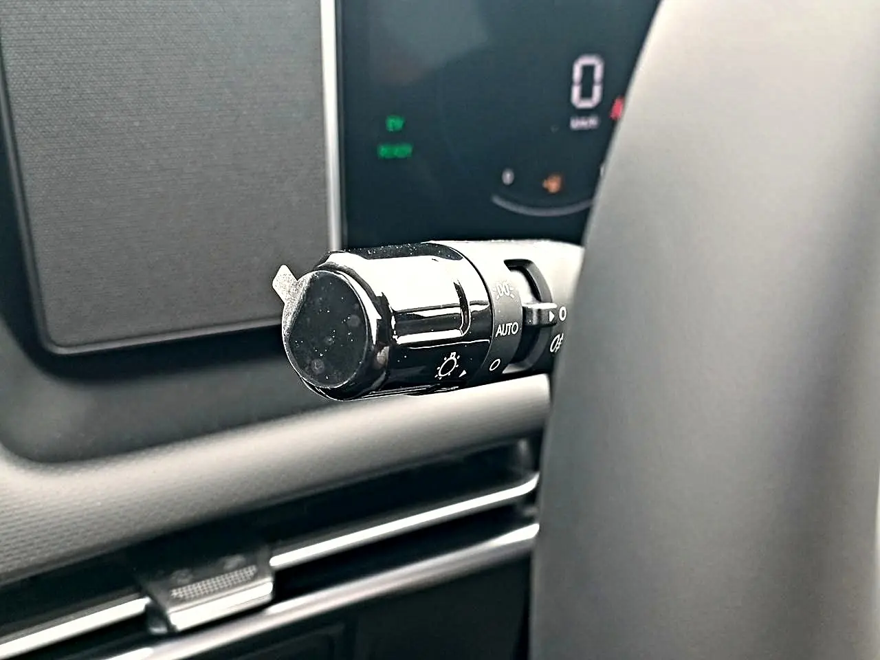 Gros plan sur la commande des phares noire à gauche du volant dans l’habitacle du Hyundai Tucson gris ecotronique 2026.