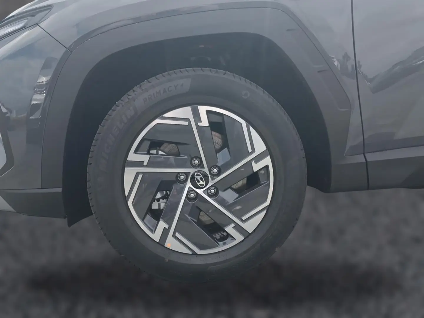 Gros plan sur la roue avant gauche du Hyundai Tucson gris ecotronique avec jante alliage 17 pouces au design moderne.