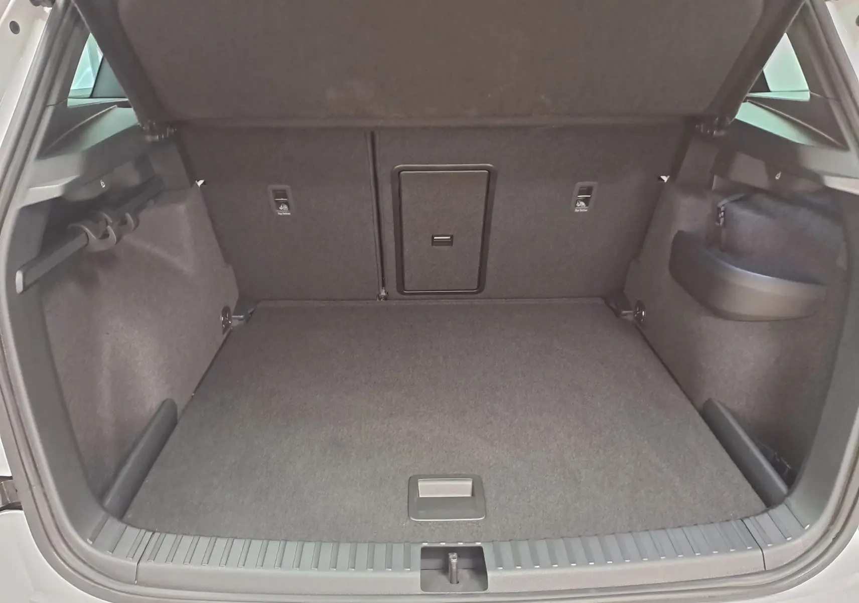Coffre ouvert vu de l'arrière d'un Skoda Karoq blanc lune, montrant un espace de chargement propre et spacieux.
