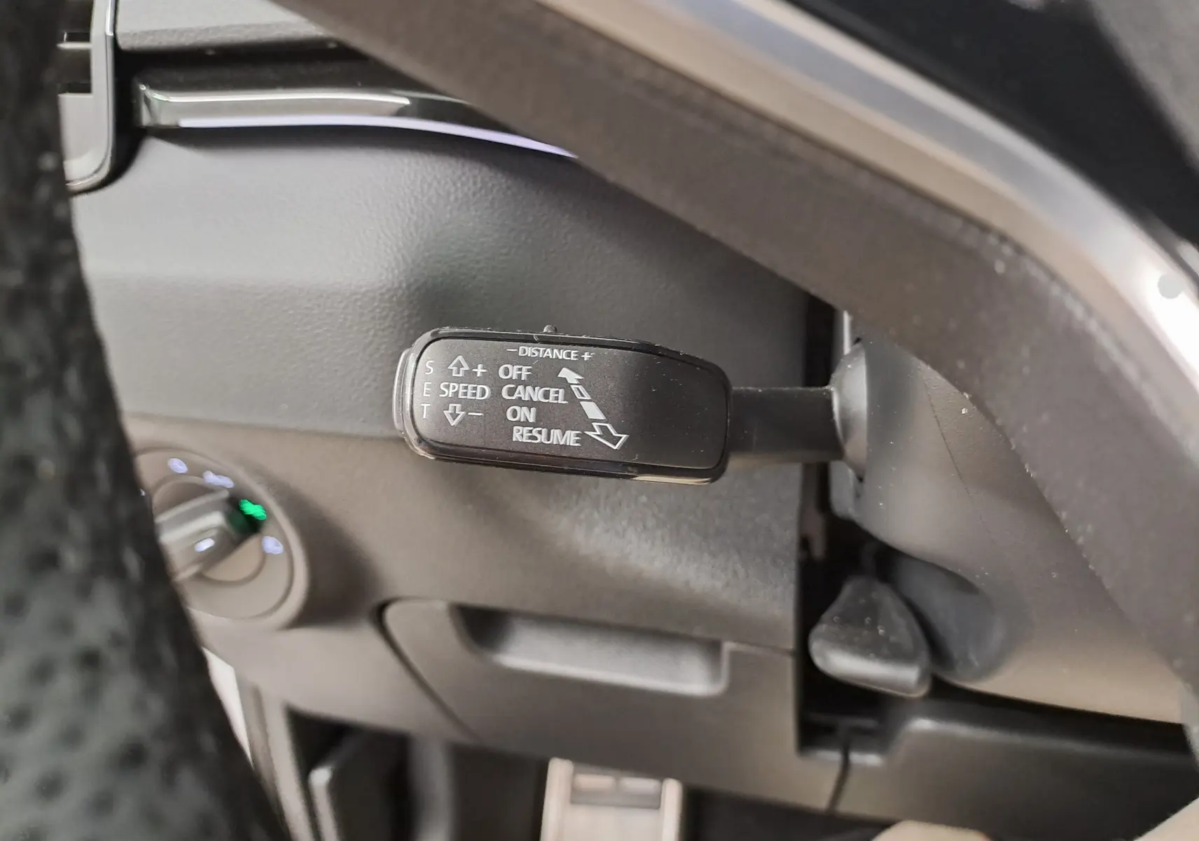 Gros plan sur le commodo de régulateur de vitesse du SKODA KAROQ 1.5 TSI 150 DSG7, intérieur noir.