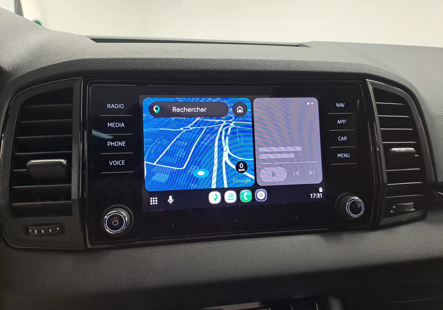 Écran central tactile du tableau de bord du Skoda Karoq blanc lune, affichant la navigation GPS et commandes multimédia.