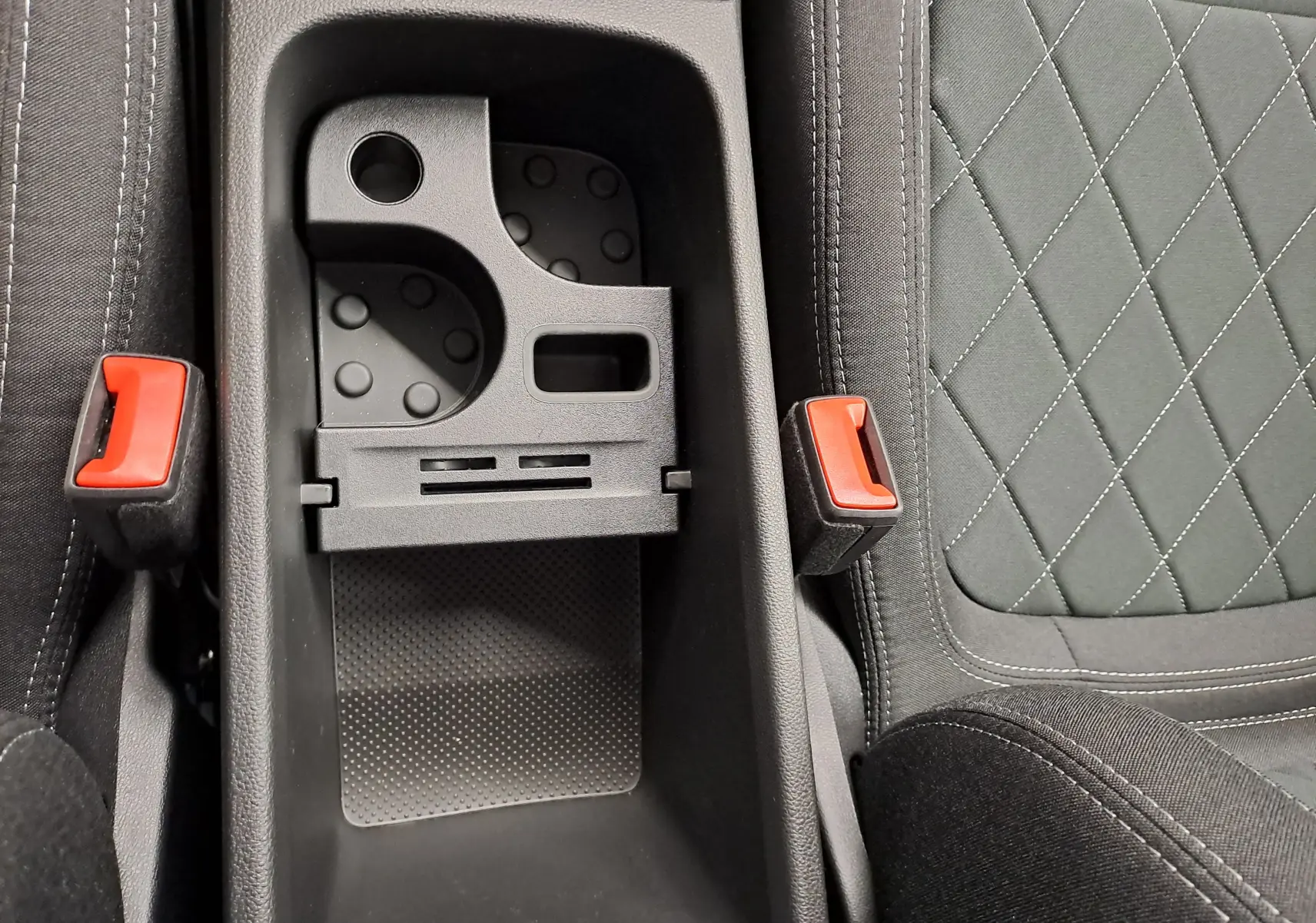 Vue rapprochée de la console centrale noire et des sièges gris à surpiqûres croisées du Skoda Karoq 2025.