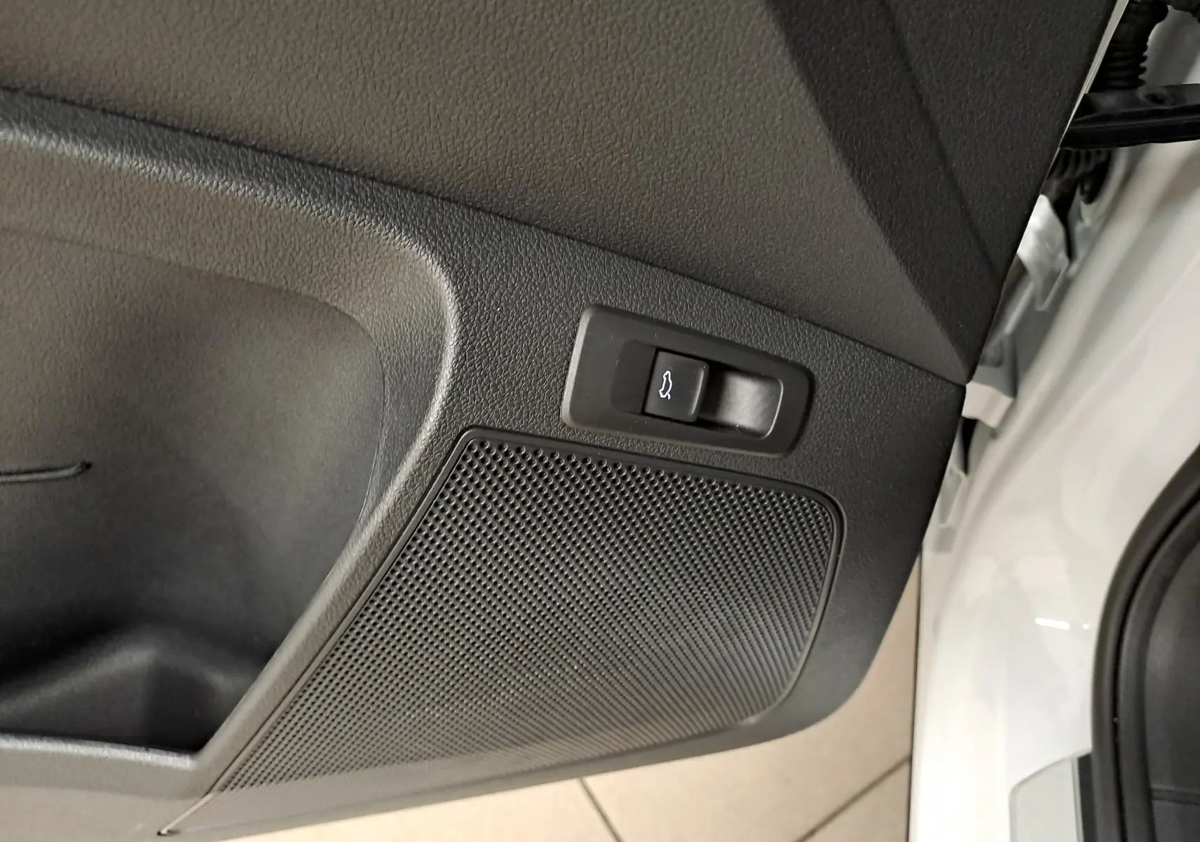 Détail du bouton d'ouverture électrique du hayon sur la porte arrière droite d'un Skoda Karoq blanc lune.