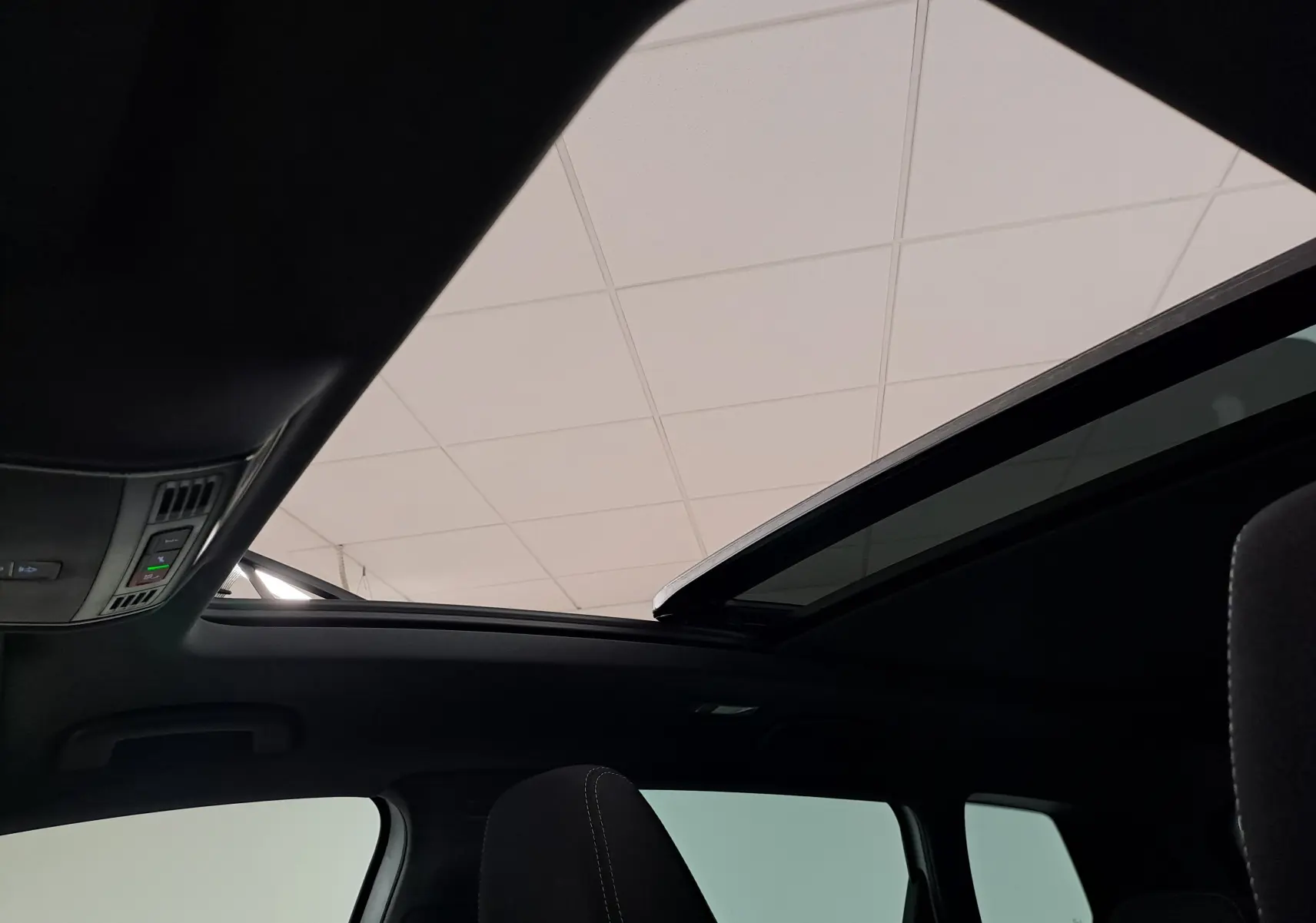 Vue intérieure du toit ouvrant panoramique en verre du Skoda Karoq blanc lune, avec commandes intégrées au plafond.