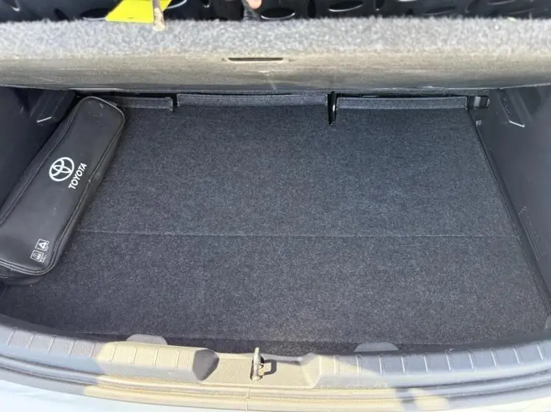 Coffre ouvert d'une Toyota Yaris 2020 gris métal, montrant un espace de rangement propre avec une trousse Toyota noire sur le côté.