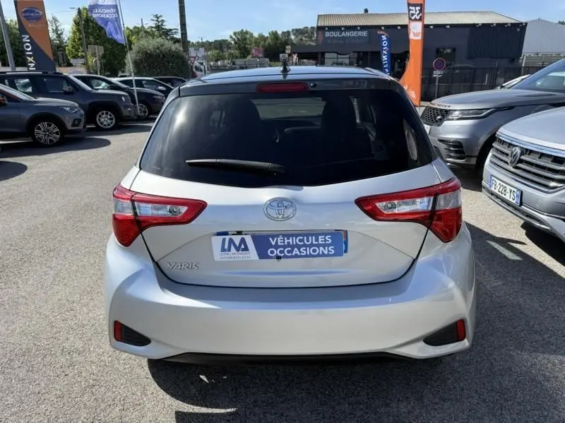 Vue arrière d'une Toyota Yaris gris métal 2020 garée en extérieur avec plaque "Véhicules Occasions" visible