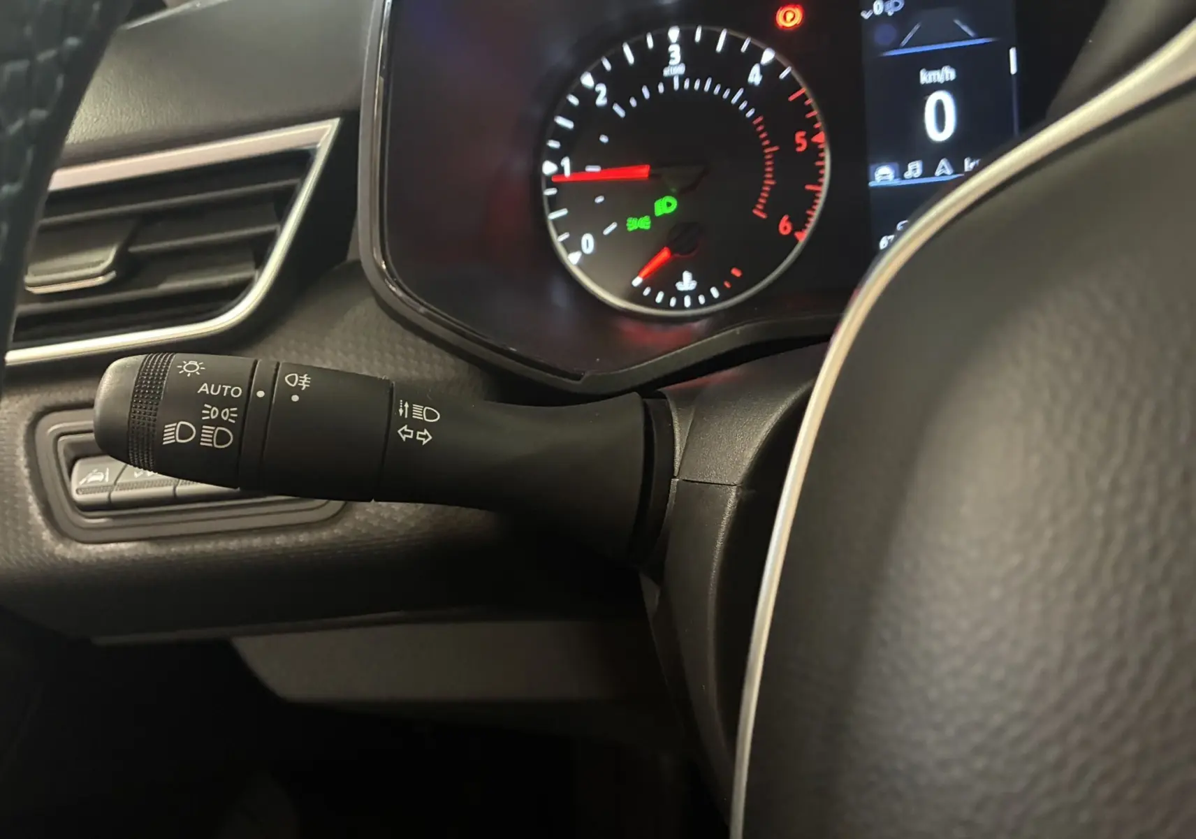 Gros plan sur la manette des feux et le tableau de bord numérique d'une Renault Clio 1.5 BlueDCI Business 2022 gris.