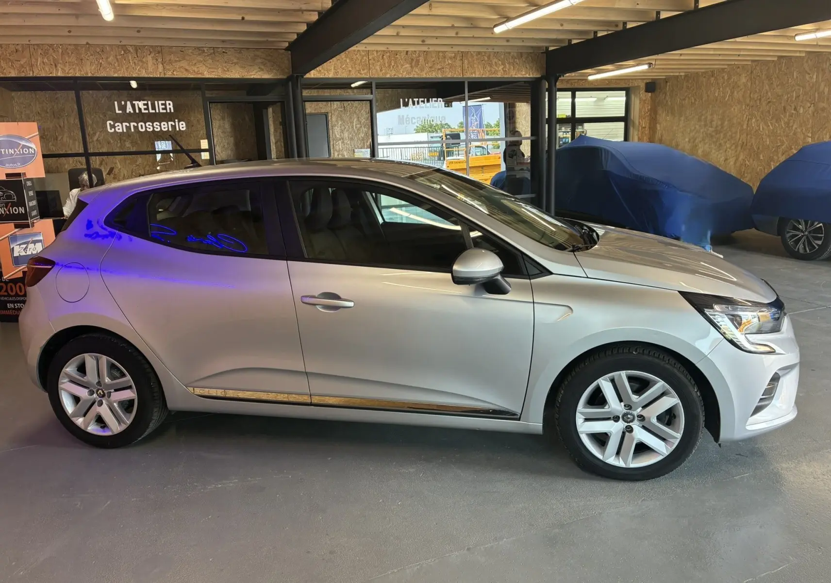 Profil côté gauche d'une Renault Clio 1.5 BlueDCI Business gris 2022, avec jantes alliage et vitres teintées.