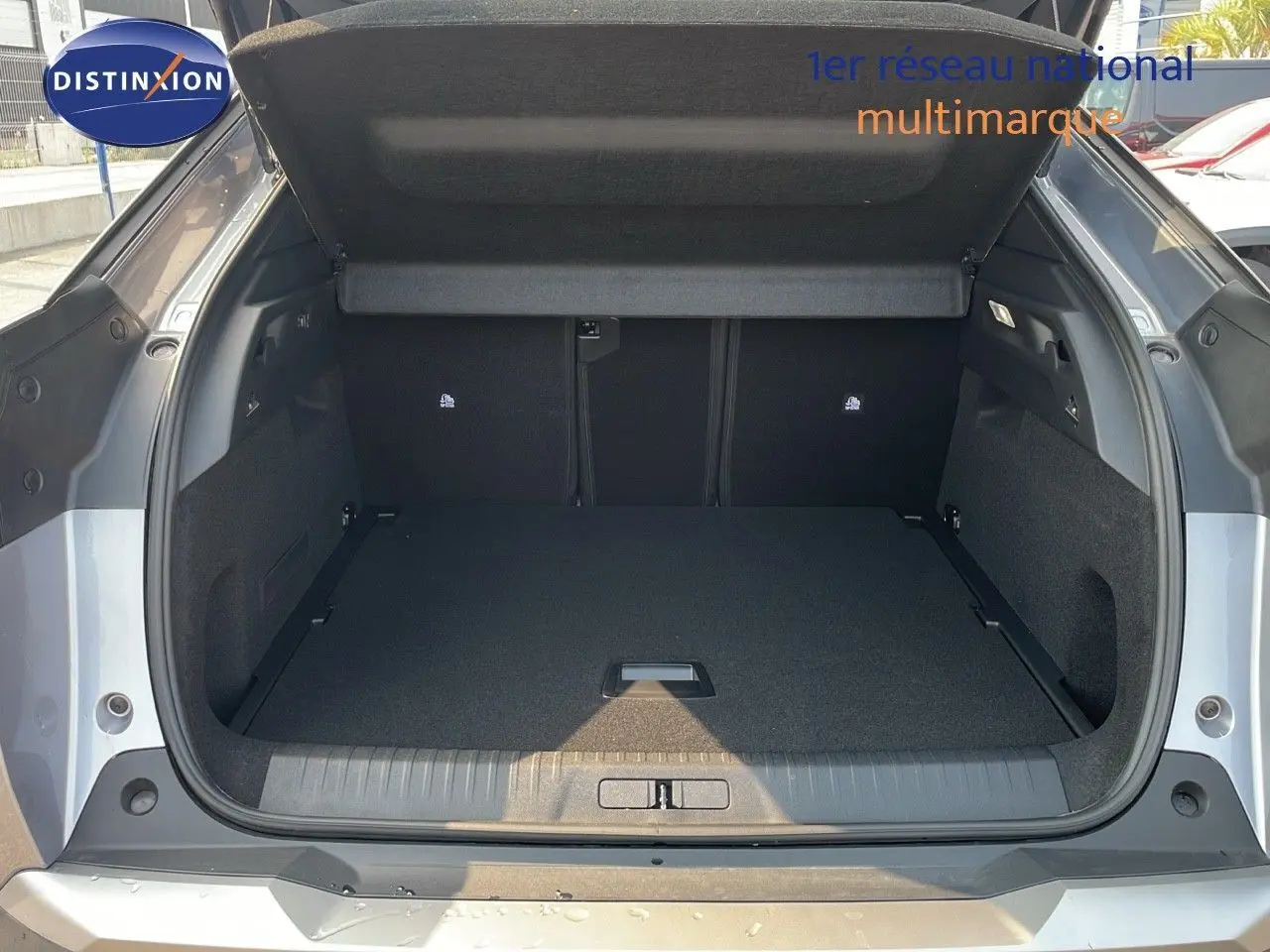 Coffre ouvert vu de l'arrière d'un Peugeot 3008 Hybrid gris Artense Metal, espace de chargement spacieux et propre.