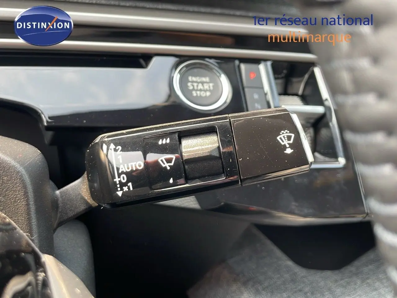 Gros plan sur la commande d’essuie-glace et bouton start du tableau de bord intérieur du Peugeot 3008 gris Artense 2025 hybride