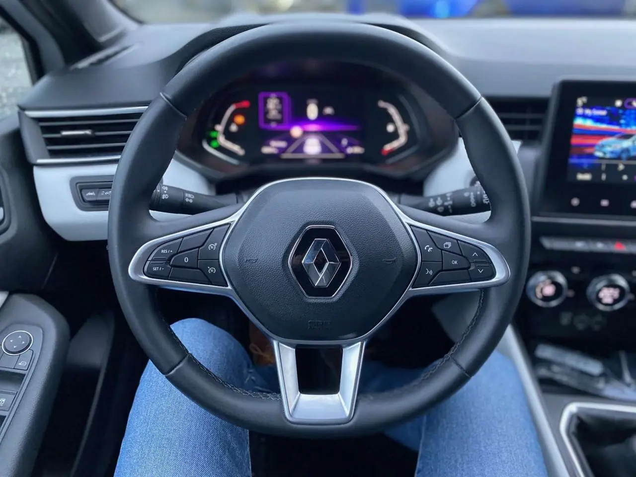 Vue centrée sur le volant noir de la Renault Clio 2023 avec tableau de bord numérique et écran tactile visible.