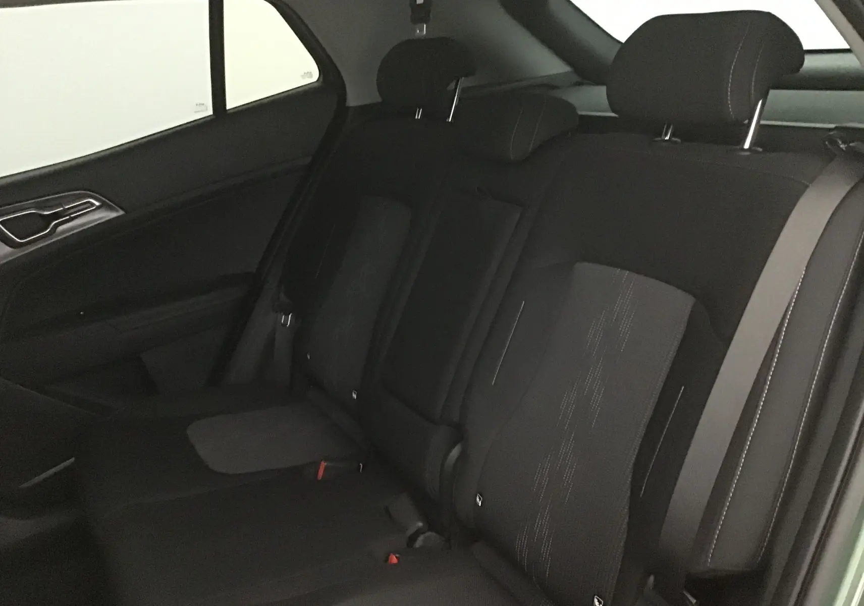 Vue intérieure du siège arrière côté droit du Kia Sportage blanc 2025, avec appuie-têtes et ceinture de sécurité visibles.