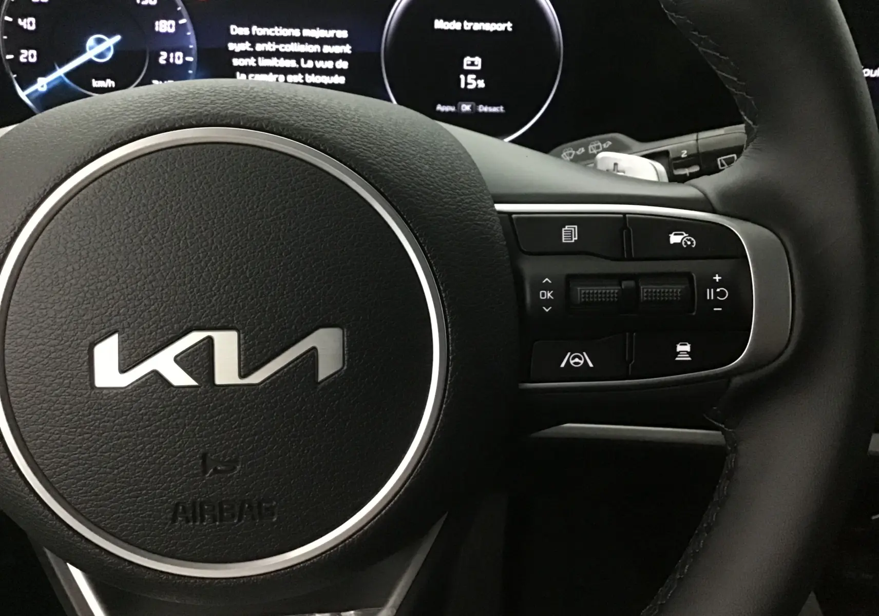 Gros plan sur le volant cuir du Kia Sportage 2025 avec commandes intégrées et combiné d'instrumentation digital.