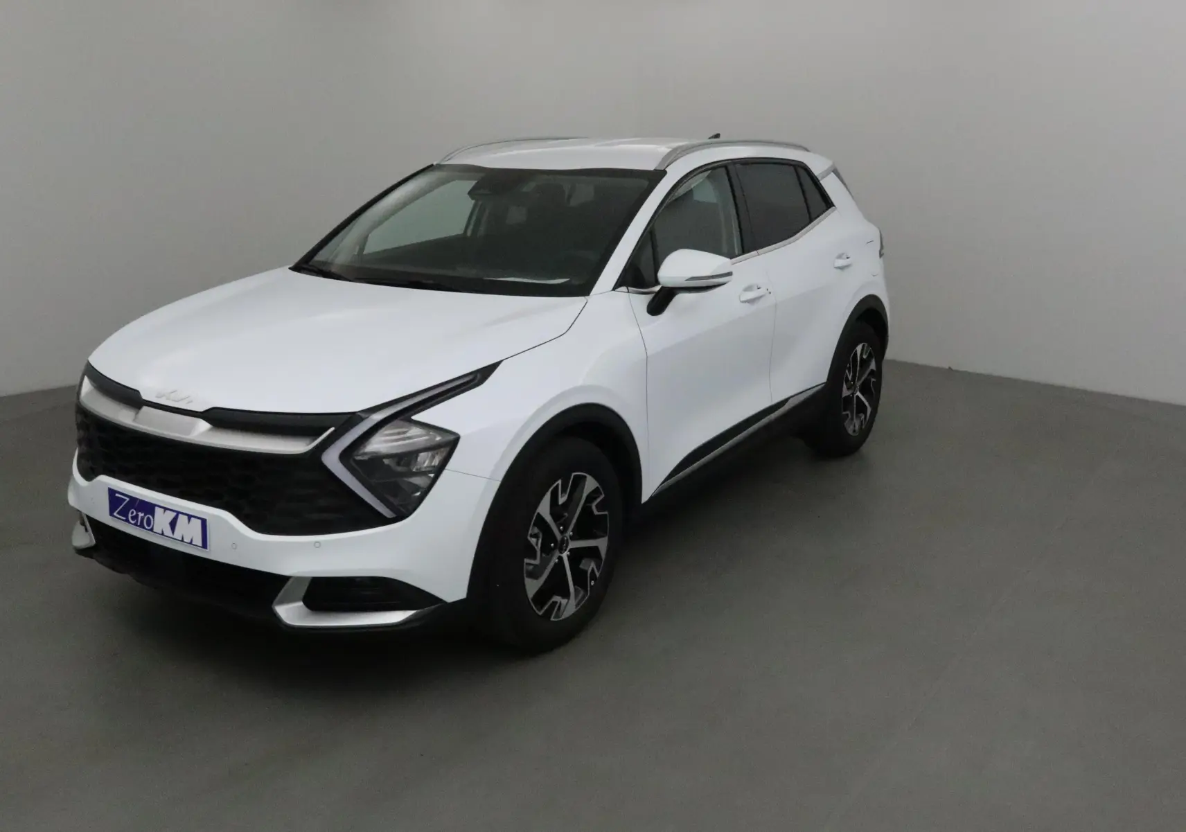 KIA SPORTAGE blanc en 3/4 avant droit, avec calandre noire distinctive et jantes alliage noires.
