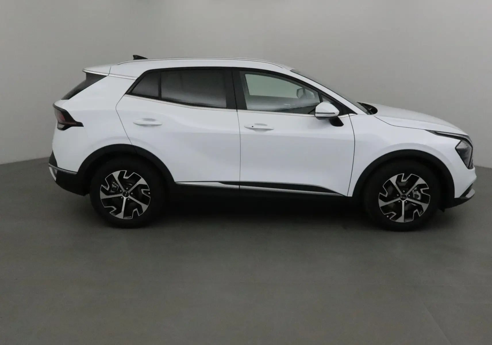 Profil côté droit du Kia Sportage blanc 2025 avec jantes alliage et lignes modernes distinctives.