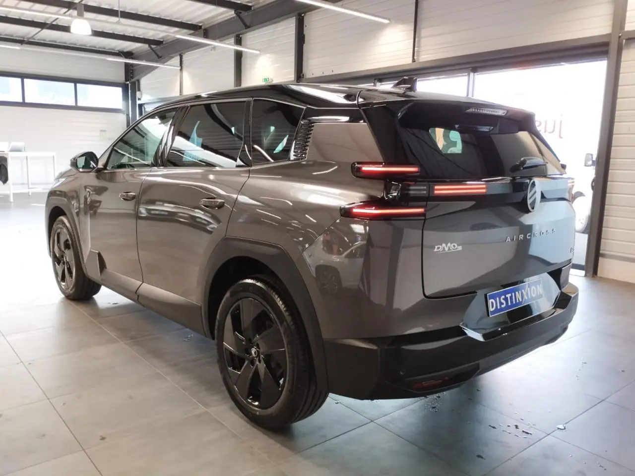 Vue 3/4 arrière droit d'un Citroën C5 Aircross gris platine avec feux arrière LED et jantes alliage noires.