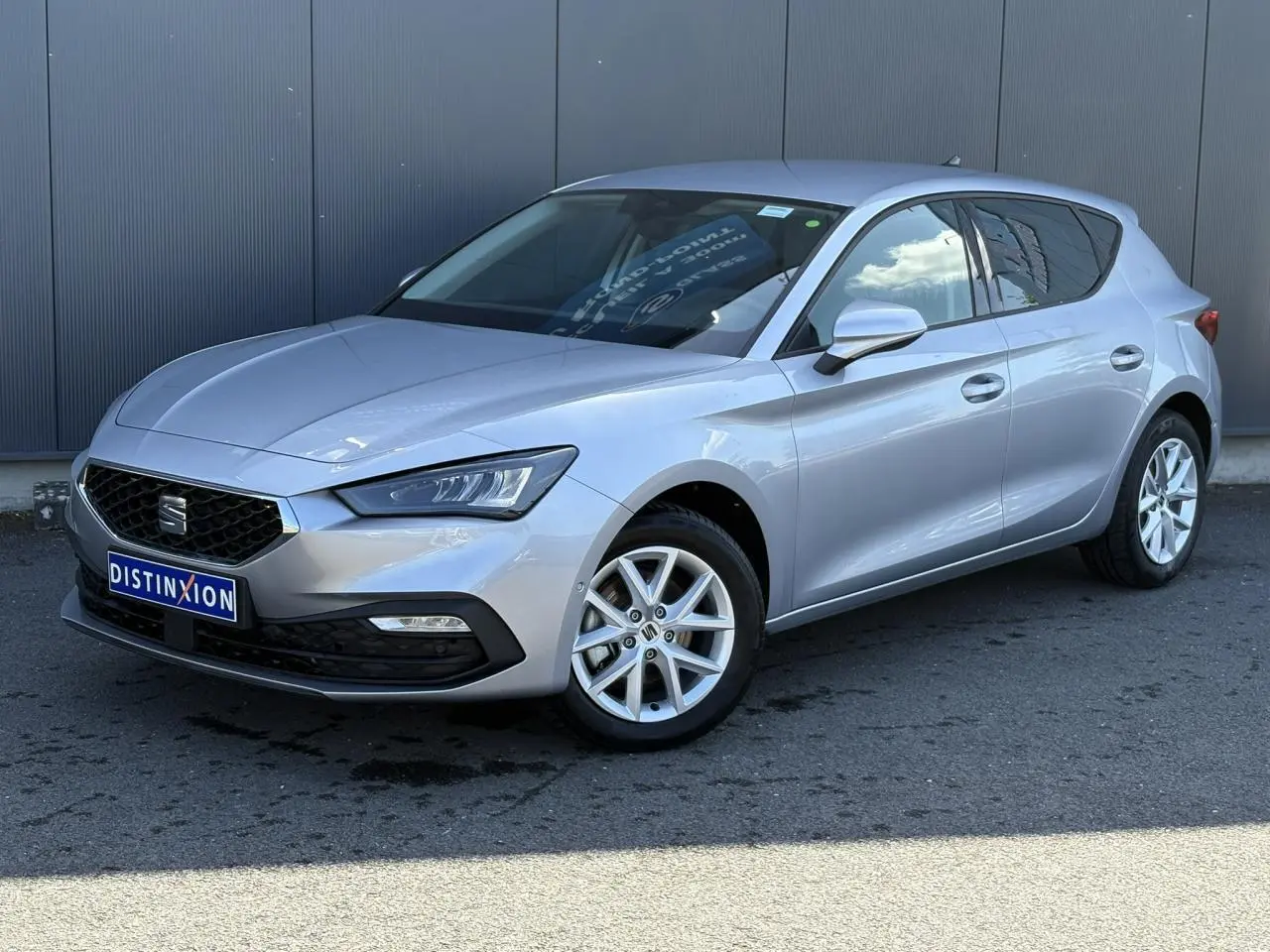 SEAT Leon 2024 gris argent vue 3/4 avant droit avec jantes alliage et vitres arrière surteintées.