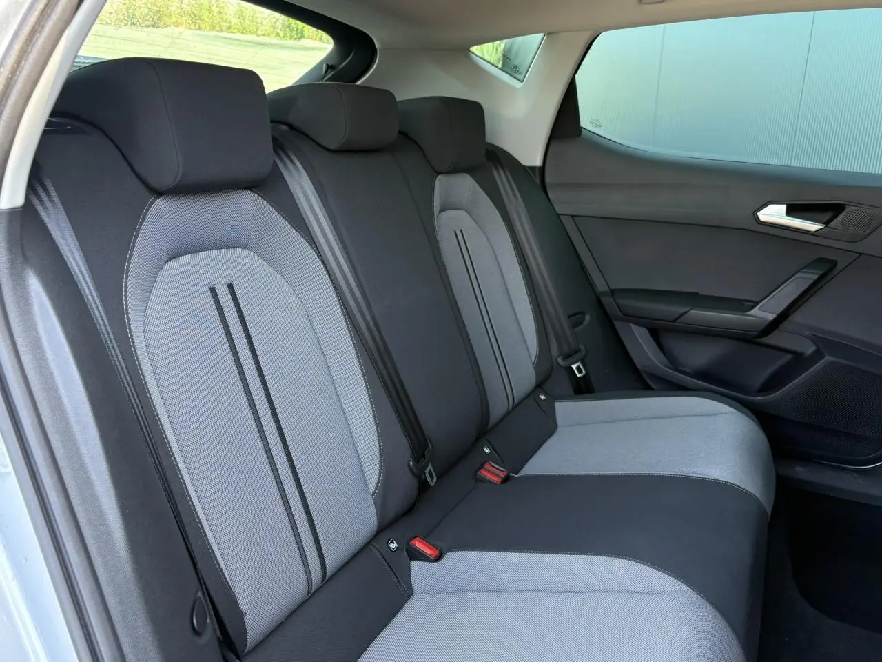 Vue latérale droite des sièges arrière gris clair et noir de la SEAT LEON 2.0 TDI 2024 avec vitres surteintées.