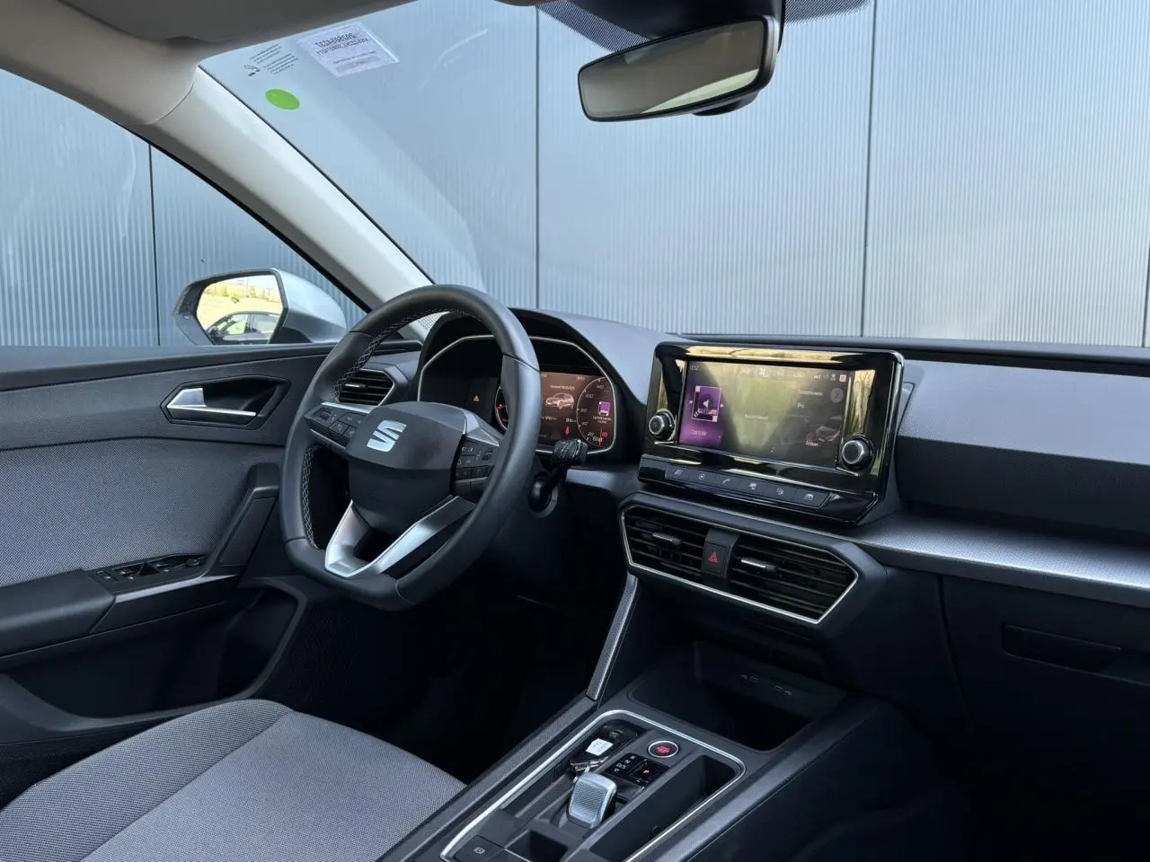 Intérieur de la SEAT LEON 2024 vu côté conducteur, volant cuir multifonction et écran tactile central.